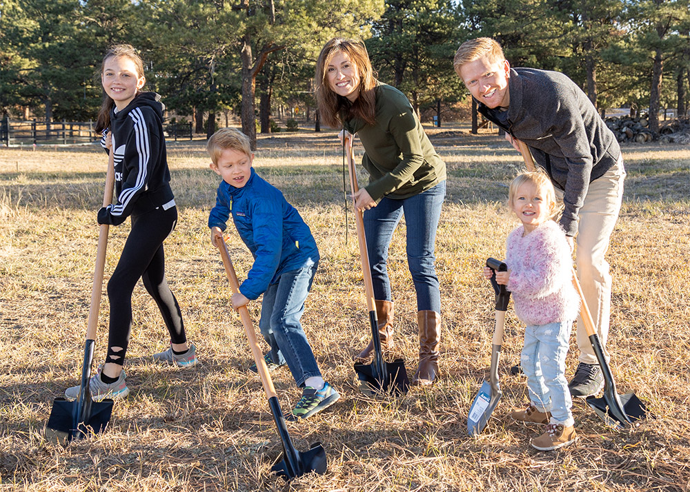 A family breaking ground with shovels in black forest in Colorado Springs